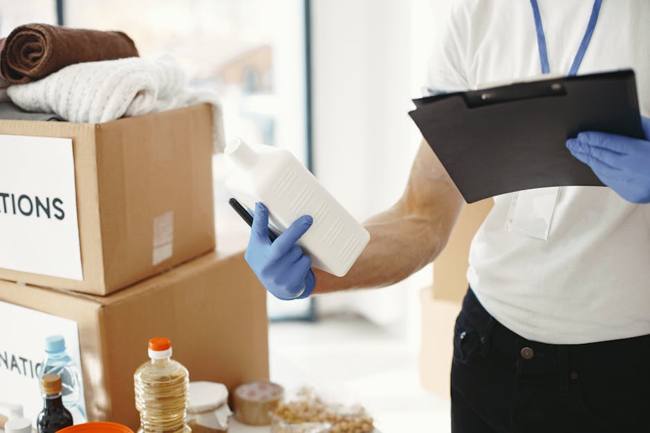 A female cleaning professional with blonde hair tied back, dressed in a white uniform, is performing surface cleaning in a residential setting. She is leaning over a bed, smoothing or inspecting a bei